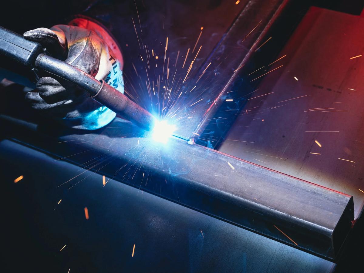 Welding a steel tube assembly, sparks across the bench